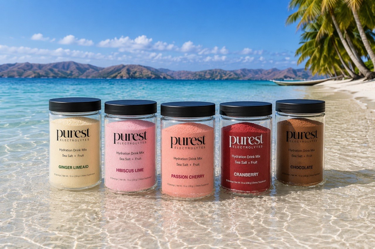 All 5 Purest Electrolyte flavors on a tropical beach - Ginger Limeaid, Hibiscus Lime, Passion Cherry, Cranberry, and Chocolate